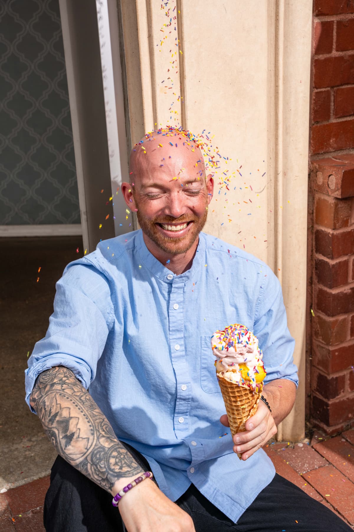 man with sprinkles being poured on head for ice cream shop