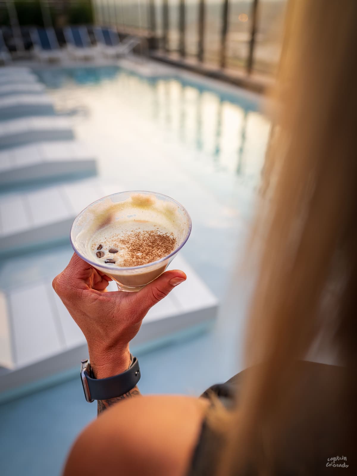 Woman drinking an espresso martini at a rooftop pool