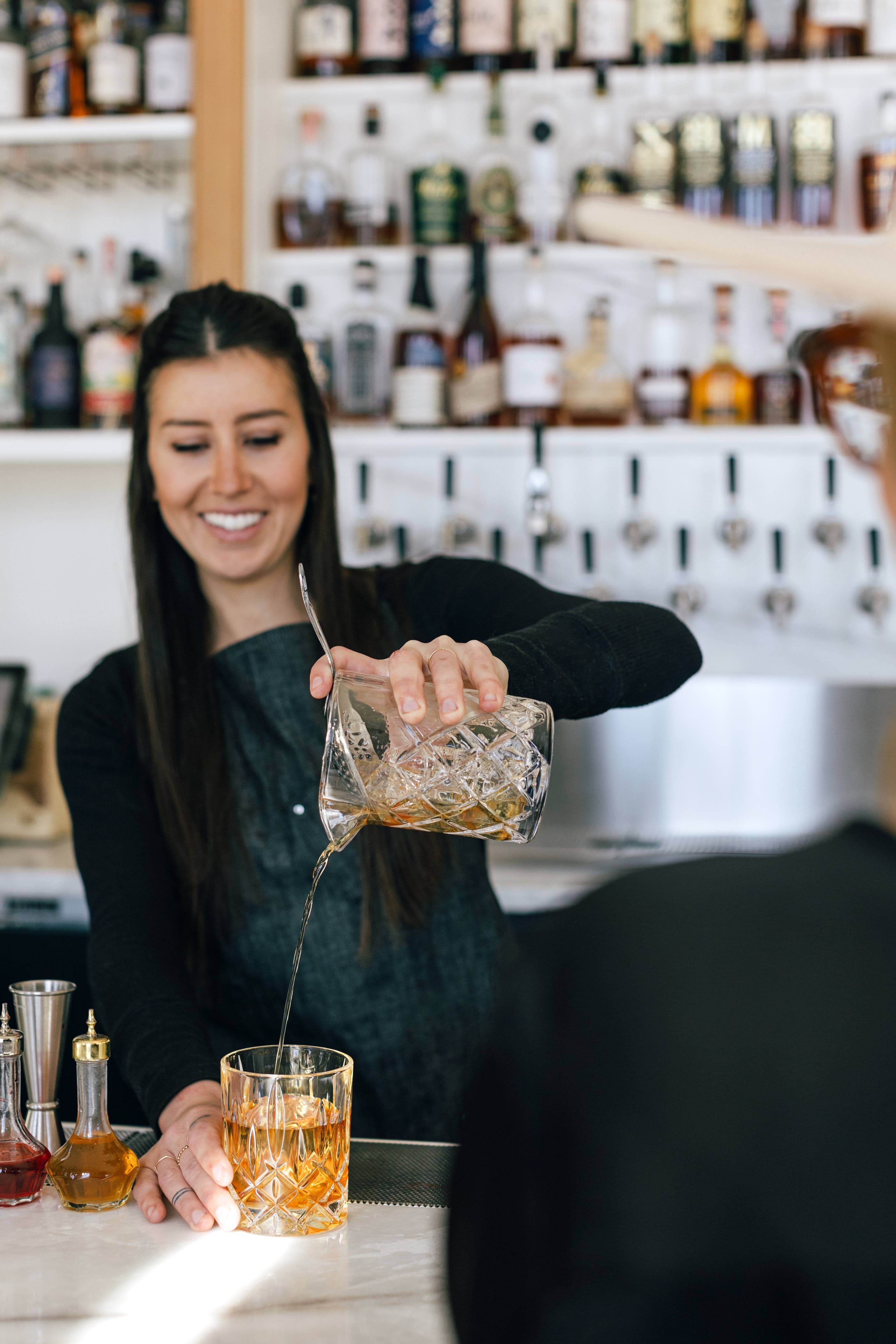 Female bartender pouring cocktail