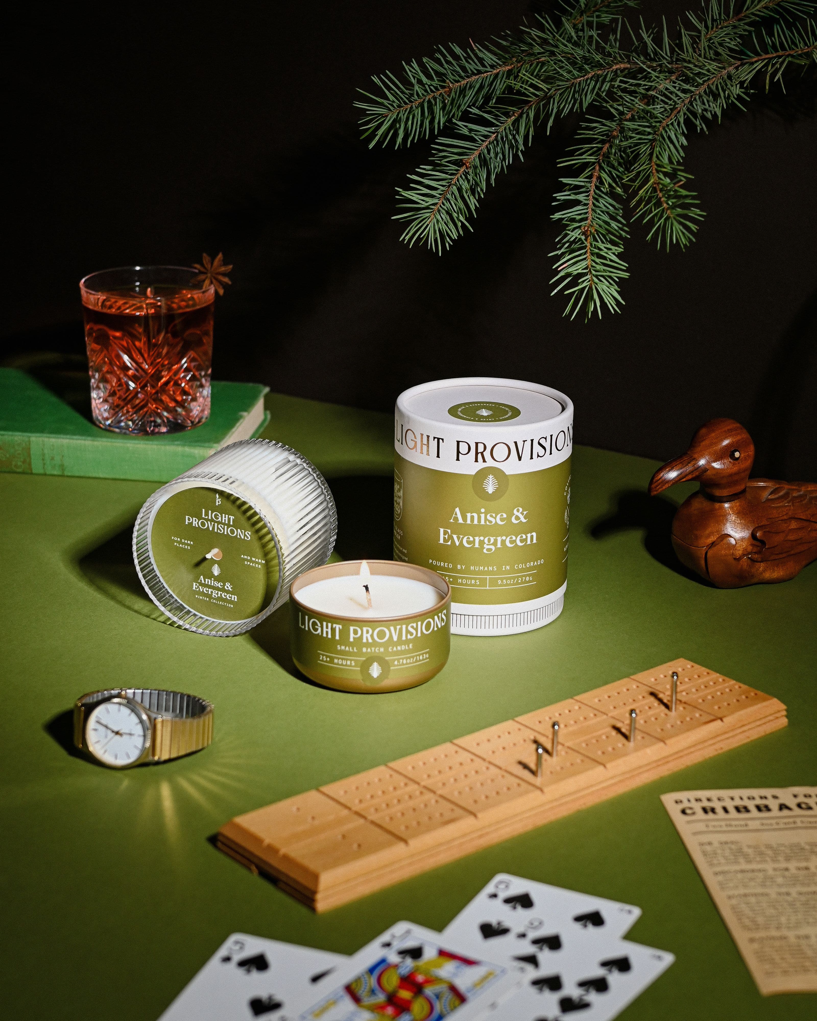 Lit evergreen candles styled in a holiday scene 