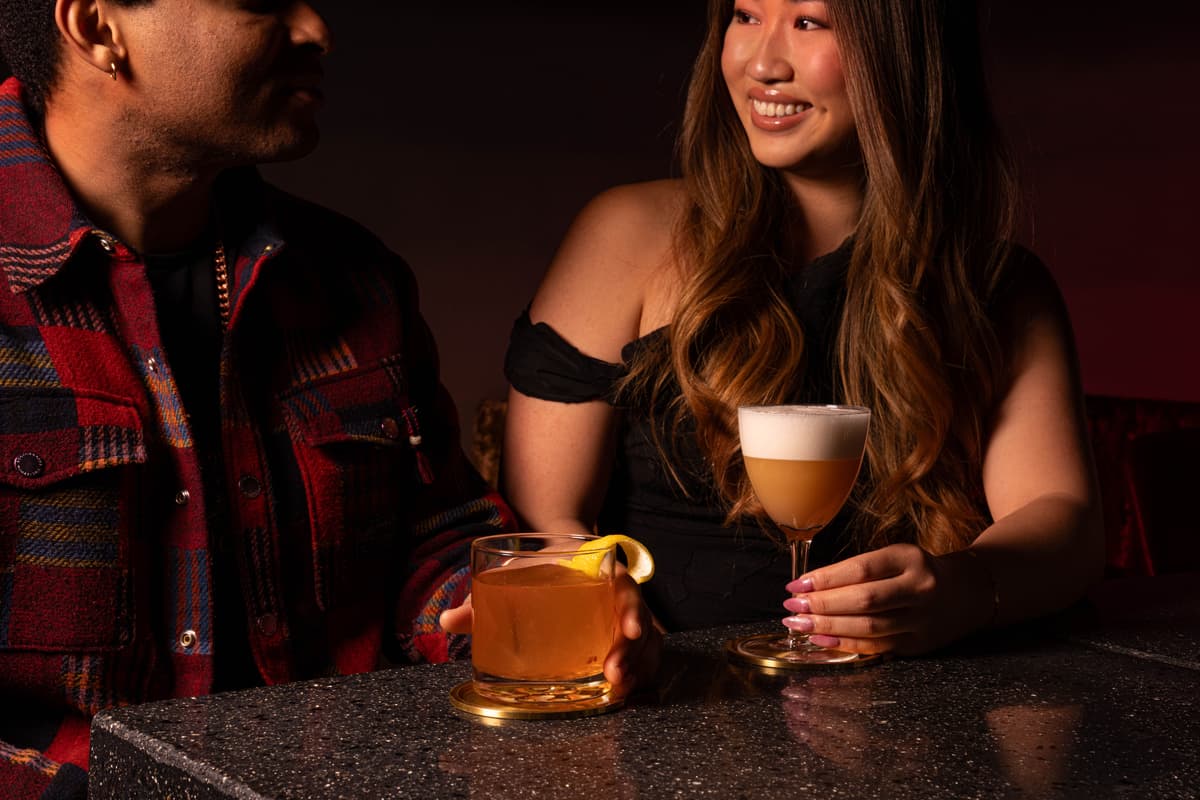 couple sitting at bar with cocktails