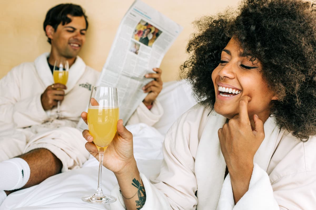 A couple enjoying breakfast in bed together in a hotel room.