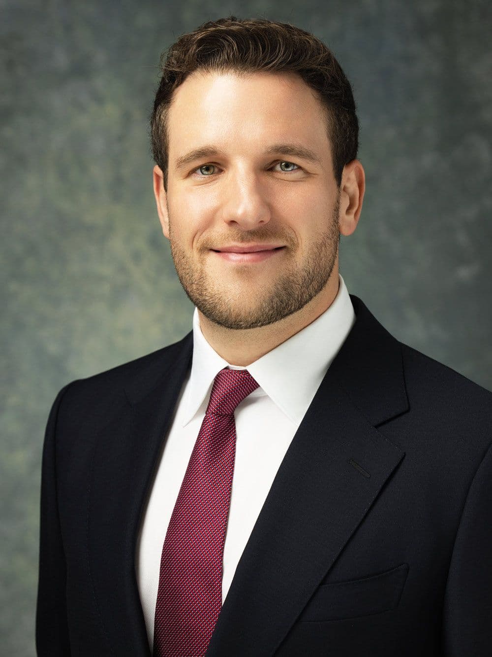 Professional headshot of a man in a suit and tie against a neutral background, photographed in Denver.